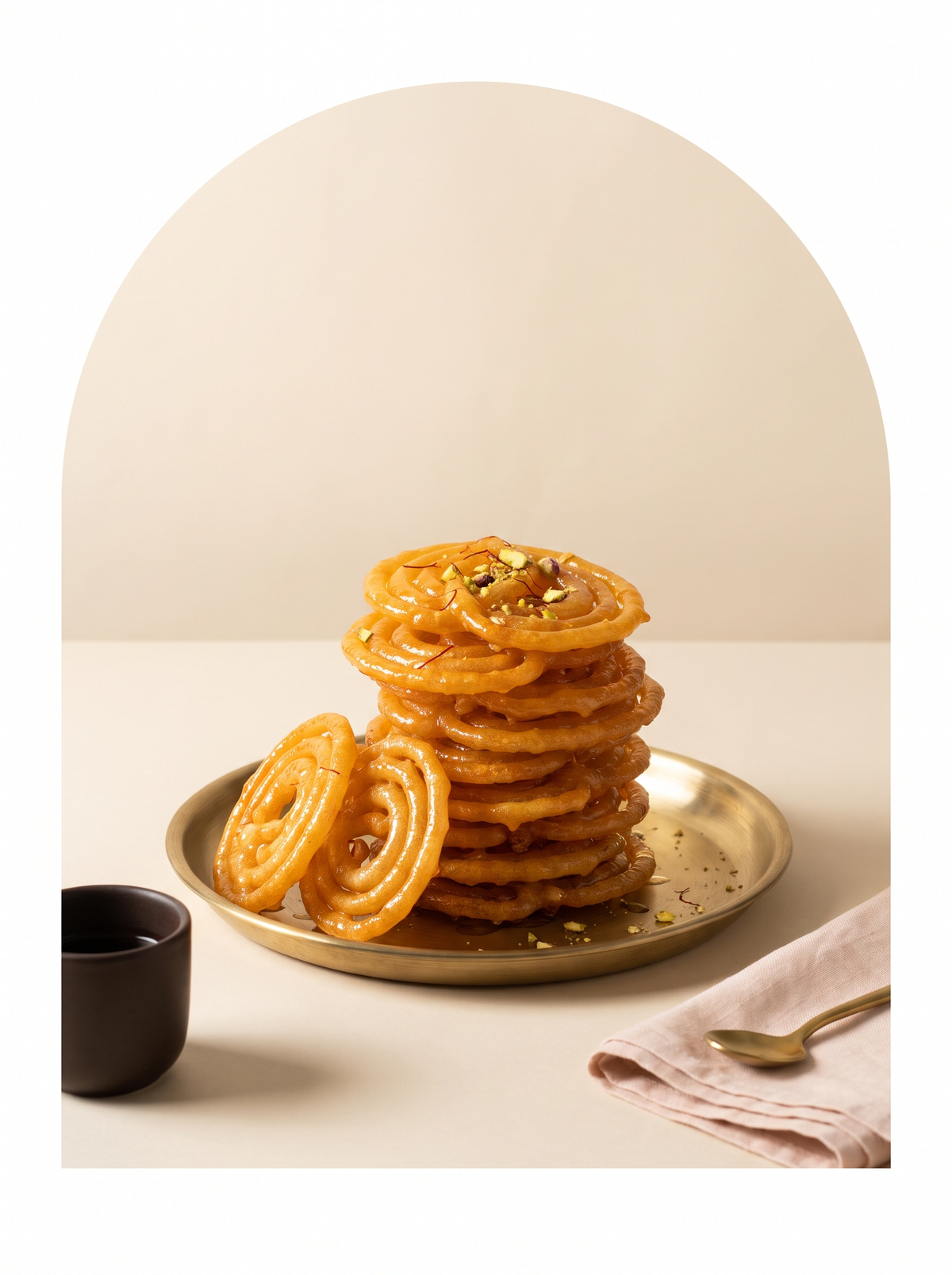 Golden jalebi spirals piled on a brass thali
