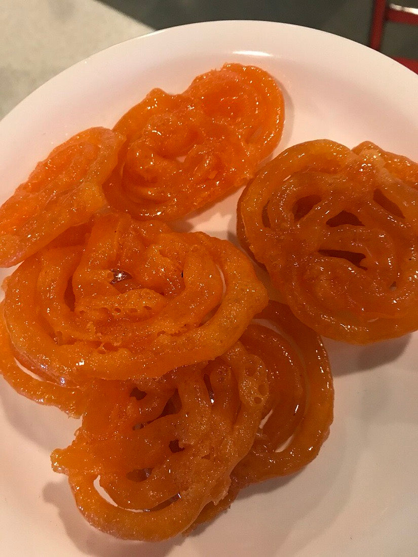 Bright orange jalebi spirals piled on a plate